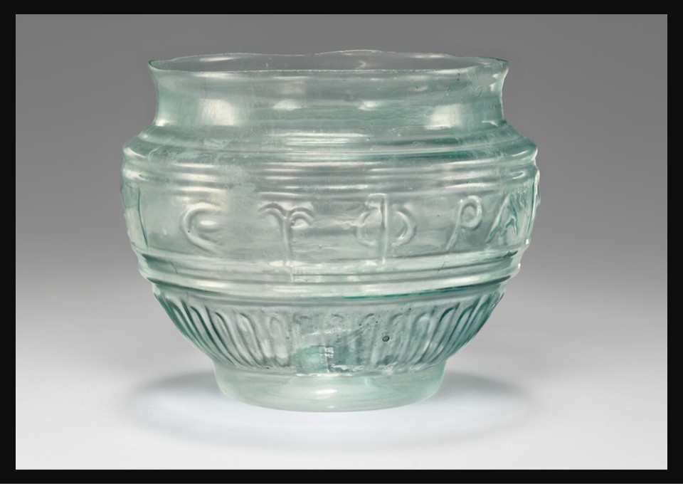 Small blue-green mold-blown Roman glass cup, possibly from the workshop of Ennion, decorated with a Greek inscription and ribbed patterns, first half of the 1st century AD, Getty Villa Museum.